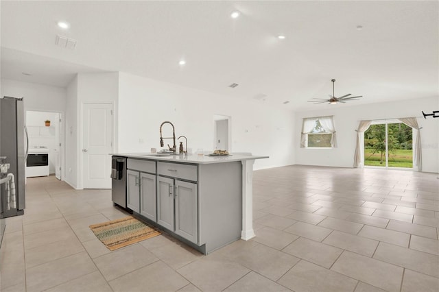 kitchen featuring gray cabinetry, stainless steel appliances, ceiling fan, sink, and an island with sink