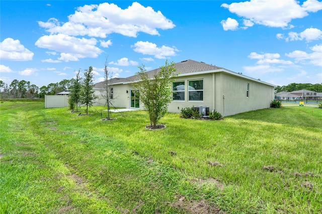 rear view of house with central AC unit and a lawn