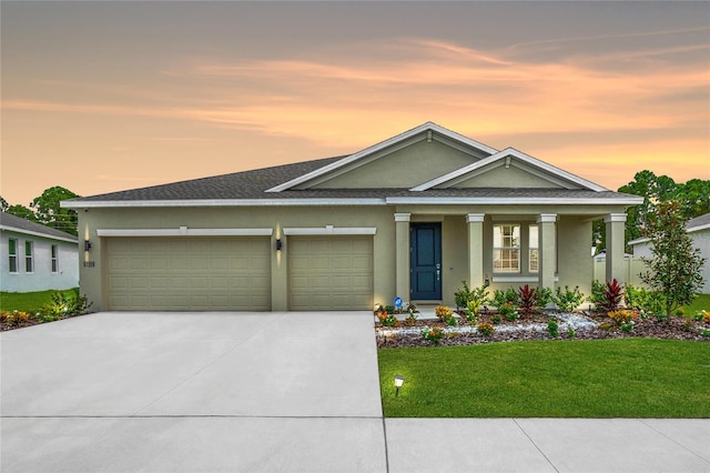 view of front of house featuring a garage, driveway, a lawn, and stucco siding