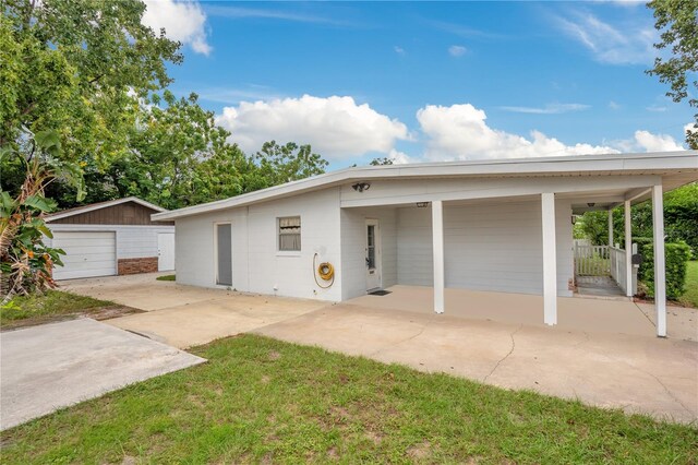 view of front facade with an outdoor structure, a carport, a front yard, and a garage