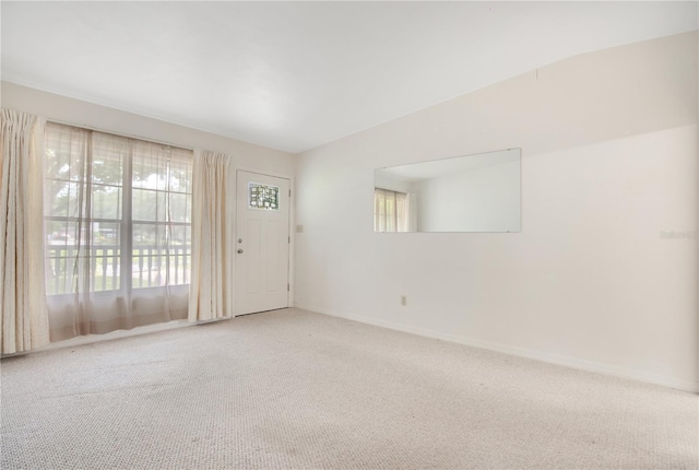 carpeted spare room featuring lofted ceiling and a healthy amount of sunlight