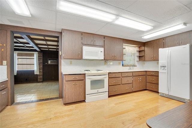 kitchen with wooden walls, white appliances, sink, light hardwood / wood-style flooring, and a wall mounted AC