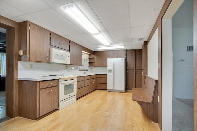 kitchen with sink, white appliances, light hardwood / wood-style flooring, a drop ceiling, and decorative backsplash