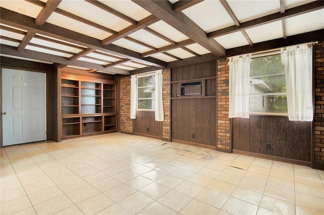 unfurnished living room featuring wooden walls, plenty of natural light, and beam ceiling