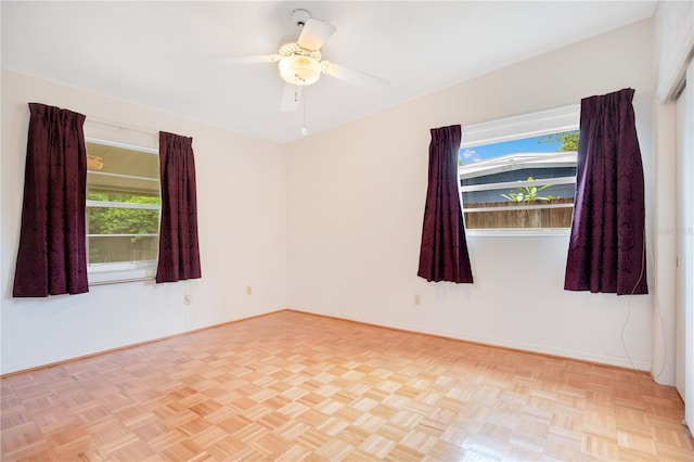 unfurnished room with ceiling fan, a wealth of natural light, and light parquet floors