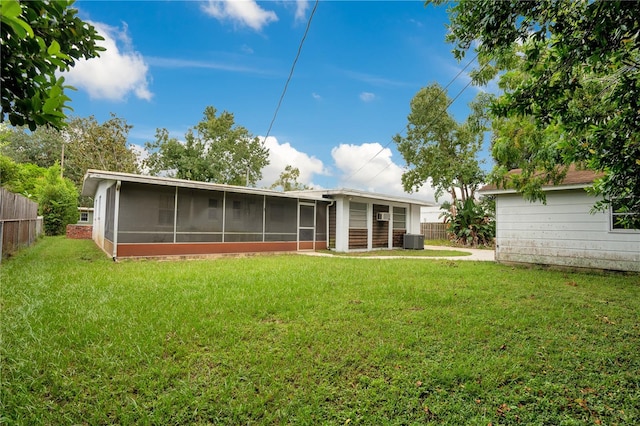 back of property with cooling unit, a sunroom, and a lawn