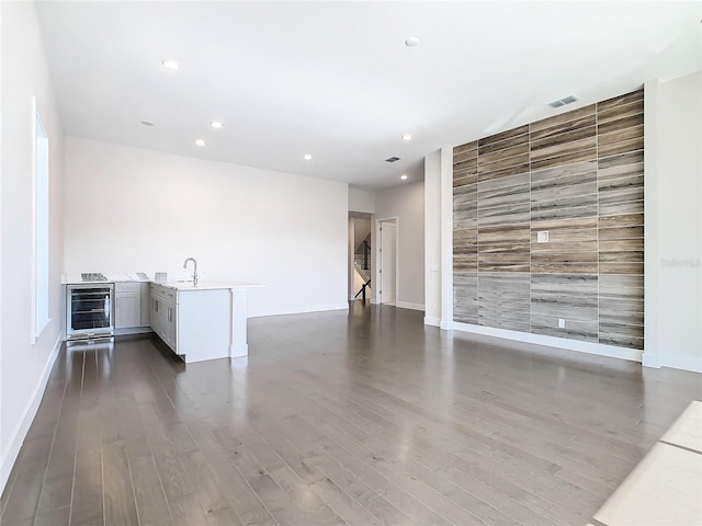 empty room with beverage cooler, dark wood-type flooring, and sink