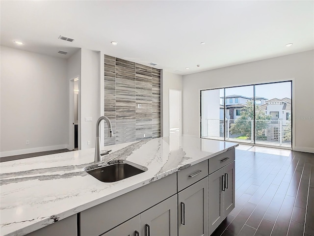 kitchen featuring gray cabinetry, light stone counters, dark hardwood / wood-style flooring, and sink