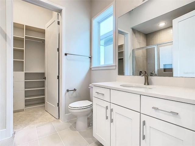 bathroom with vanity, toilet, a shower with door, and tile patterned floors