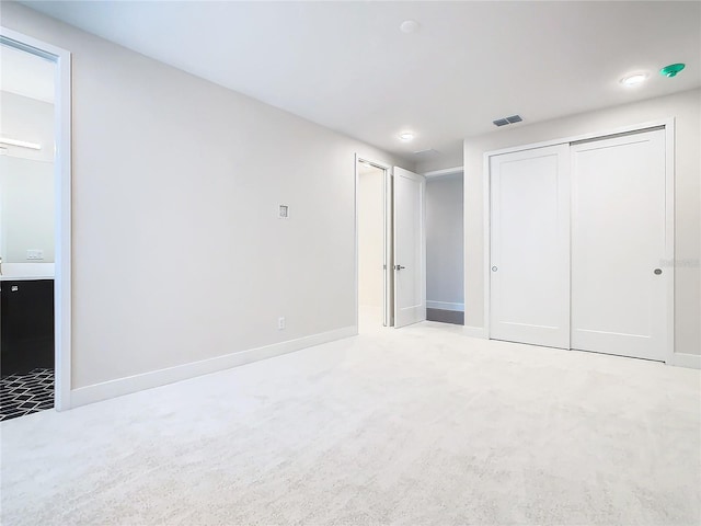 unfurnished bedroom featuring light carpet and connected bathroom