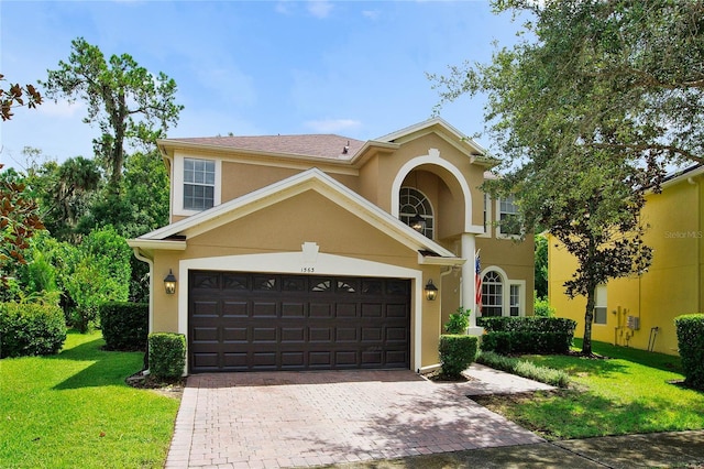 view of front of property with a front yard, decorative driveway, a garage, and stucco siding