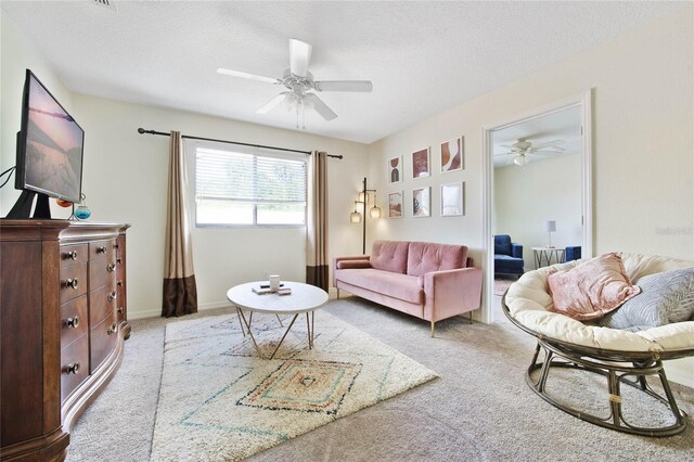 carpeted living room featuring ceiling fan and a textured ceiling