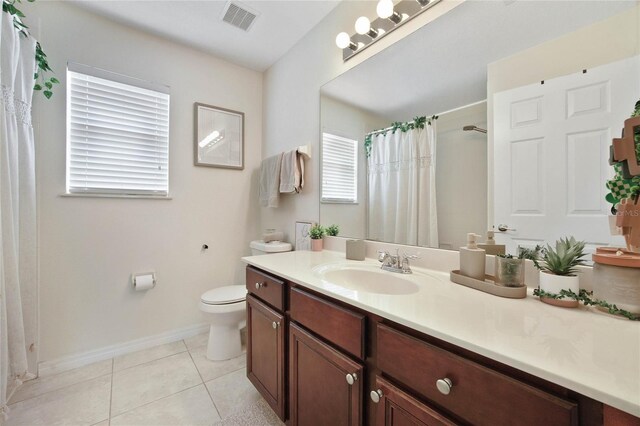 bathroom with a wealth of natural light, vanity, toilet, and tile patterned floors