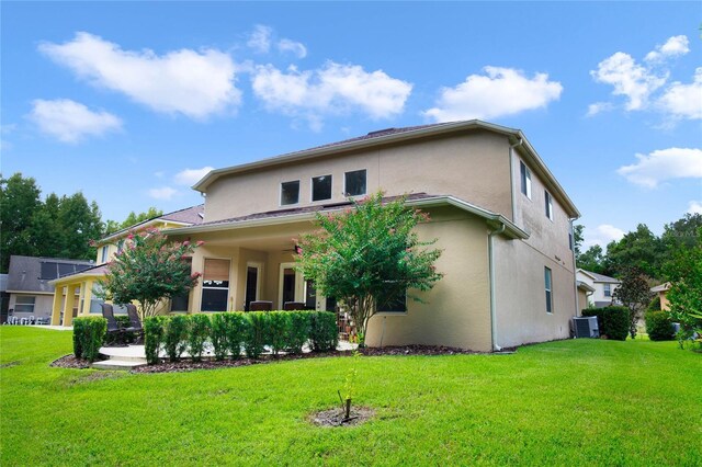 back of property with central air condition unit and a lawn