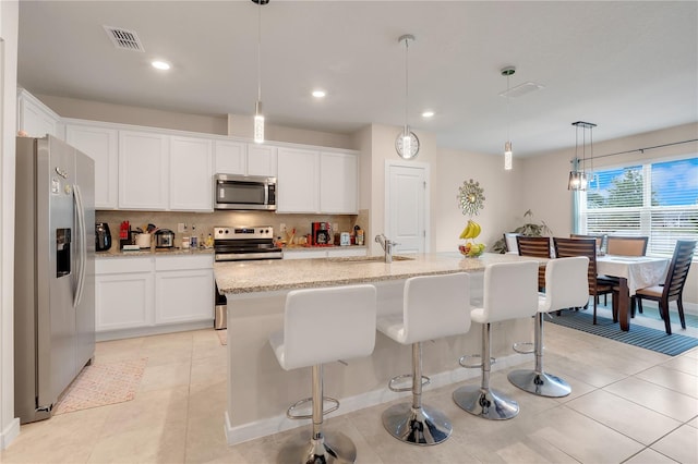 kitchen with pendant lighting, sink, white cabinets, a kitchen island with sink, and stainless steel appliances