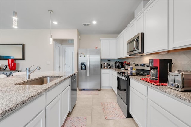 kitchen featuring pendant lighting, sink, appliances with stainless steel finishes, white cabinetry, and tasteful backsplash