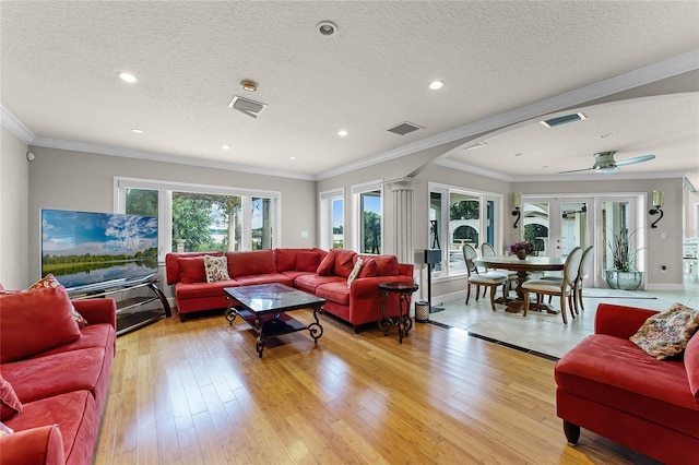 living room with light wood-type flooring, a textured ceiling, decorative columns, and ceiling fan