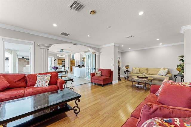 living room with light wood-type flooring, crown molding, and ornate columns