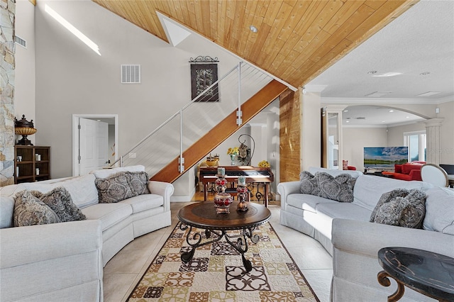 tiled living room with wooden ceiling, crown molding, ornate columns, and high vaulted ceiling