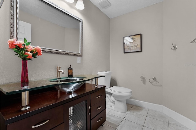 bathroom featuring a textured ceiling, vanity, toilet, and tile patterned floors