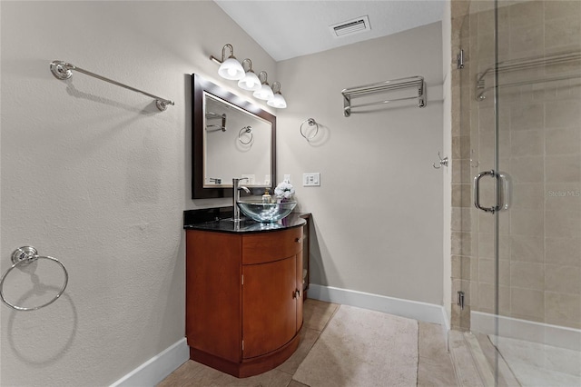 bathroom with tile patterned flooring, a shower with shower door, and vanity