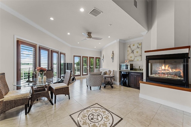 living room featuring ceiling fan, crown molding, and sink