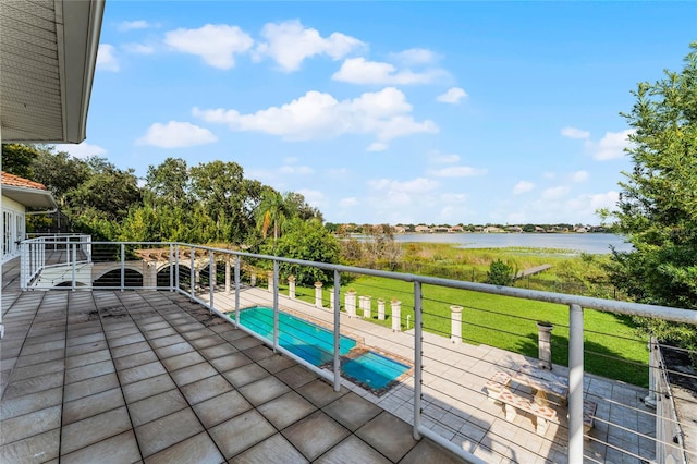 wooden terrace featuring a patio, a water view, a covered pool, and a yard