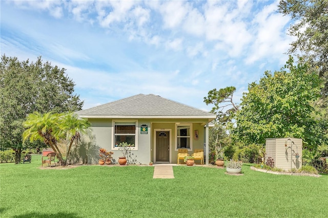 view of front of property with a front yard, roof with shingles, and stucco siding