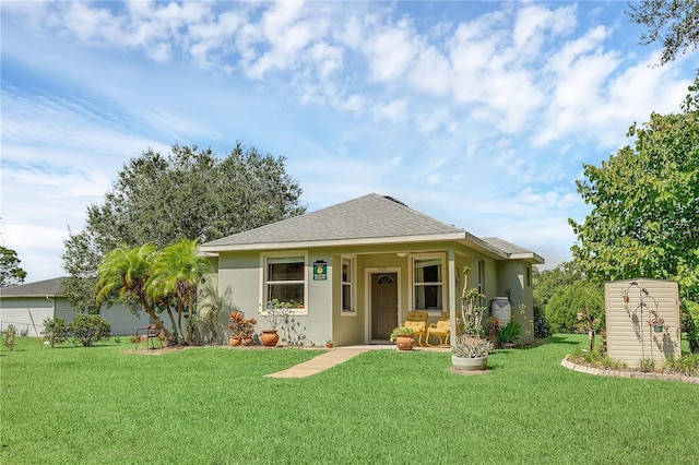 view of front facade featuring stucco siding, a shingled roof, and a front lawn