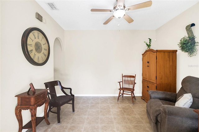 living area featuring light tile patterned flooring, visible vents, baseboards, and ceiling fan