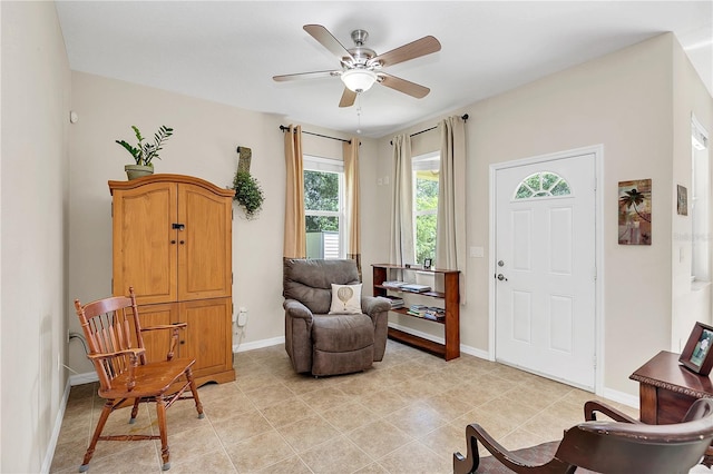 sitting room with light tile patterned floors, baseboards, and ceiling fan