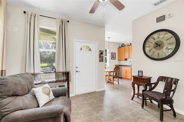 living room featuring light tile patterned floors, visible vents, ceiling fan, and baseboards