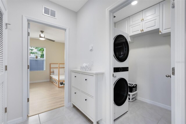 washroom featuring light hardwood / wood-style flooring, ceiling fan, and stacked washer / dryer