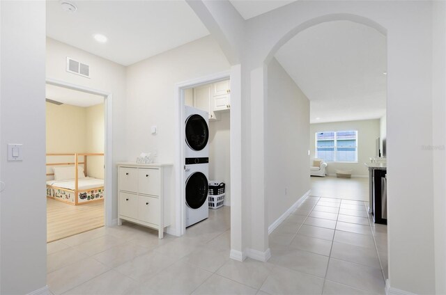 hallway featuring stacked washer / drying machine and light tile patterned flooring