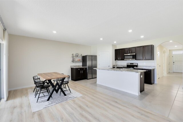 kitchen featuring stainless steel appliances, light hardwood / wood-style floors, sink, an island with sink, and a textured ceiling