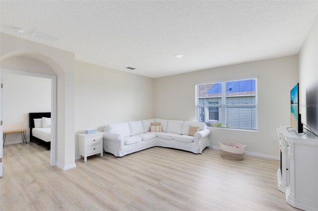 living room with light wood-type flooring and a textured ceiling