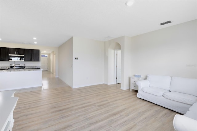 living room featuring a textured ceiling, light hardwood / wood-style flooring, and sink