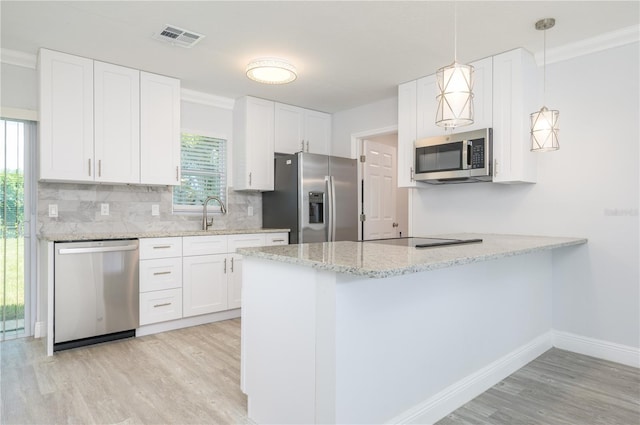 kitchen with visible vents, white cabinets, a peninsula, stainless steel appliances, and backsplash