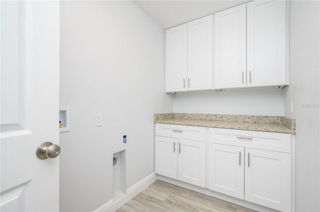 clothes washing area featuring hookup for a washing machine, light wood-style flooring, hookup for an electric dryer, baseboards, and cabinet space