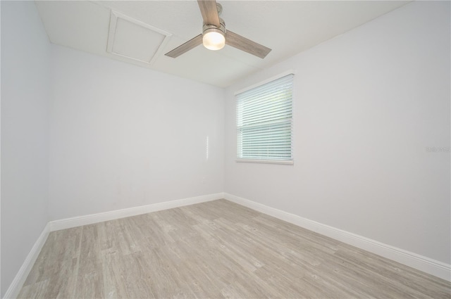 empty room with light wood finished floors, attic access, baseboards, and a ceiling fan