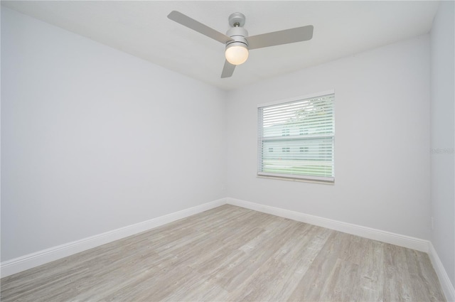 empty room featuring light wood finished floors, baseboards, and a ceiling fan