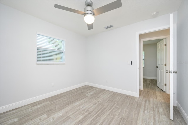 unfurnished room with baseboards, a ceiling fan, visible vents, and light wood-style floors