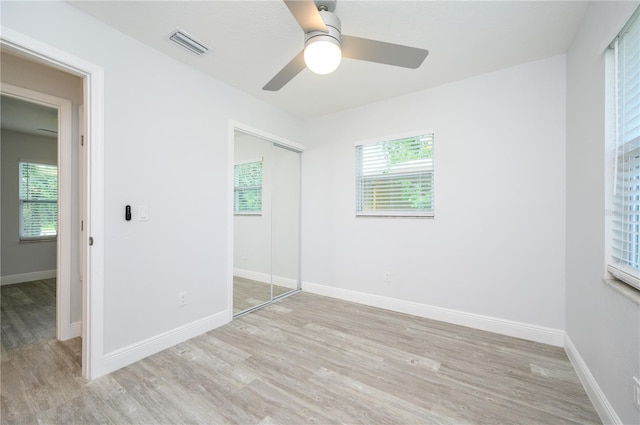 unfurnished bedroom featuring multiple windows, a closet, wood finished floors, and visible vents