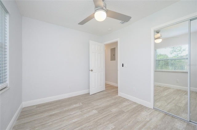 unfurnished bedroom with electric panel, baseboards, a ceiling fan, wood finished floors, and a closet