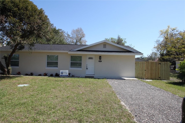 single story home featuring driveway, a front lawn, fence, and stucco siding