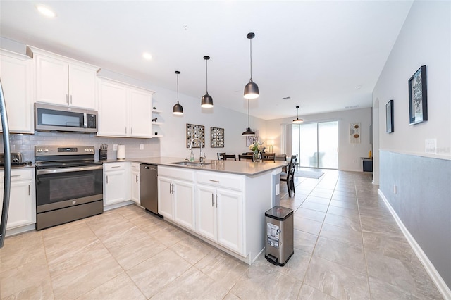 kitchen with hanging light fixtures, stainless steel appliances, sink, kitchen peninsula, and white cabinets