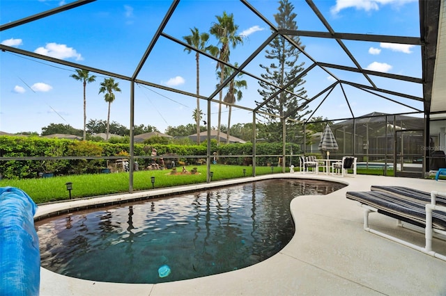 view of pool featuring glass enclosure, a lawn, and a patio