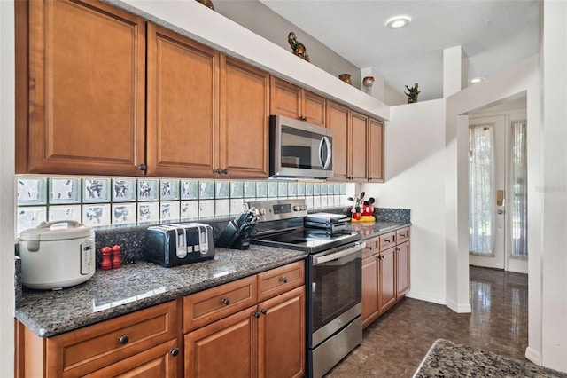 kitchen with appliances with stainless steel finishes, dark stone countertops, and tasteful backsplash