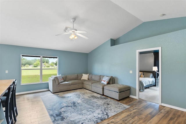 living room featuring ceiling fan, dark wood-type flooring, and vaulted ceiling