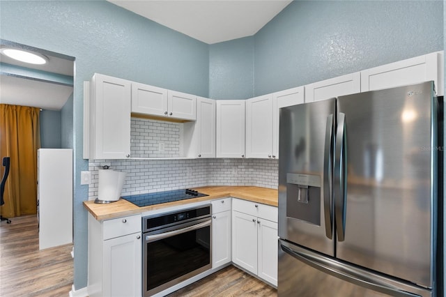 kitchen with wood counters, stainless steel appliances, white cabinetry, and light hardwood / wood-style floors